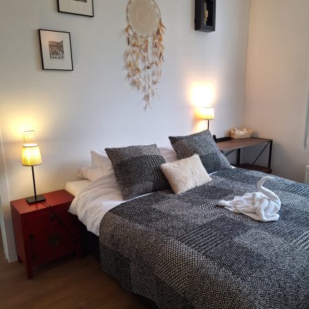 bed - schuin zijaanzicht - nachtkastjes - nachtlampen die branden - handdoek gevouwd als een zwaan